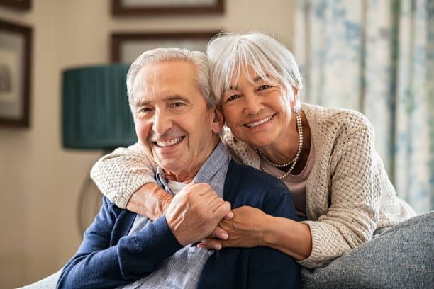 An older couple sitting close together on a sofa at home.