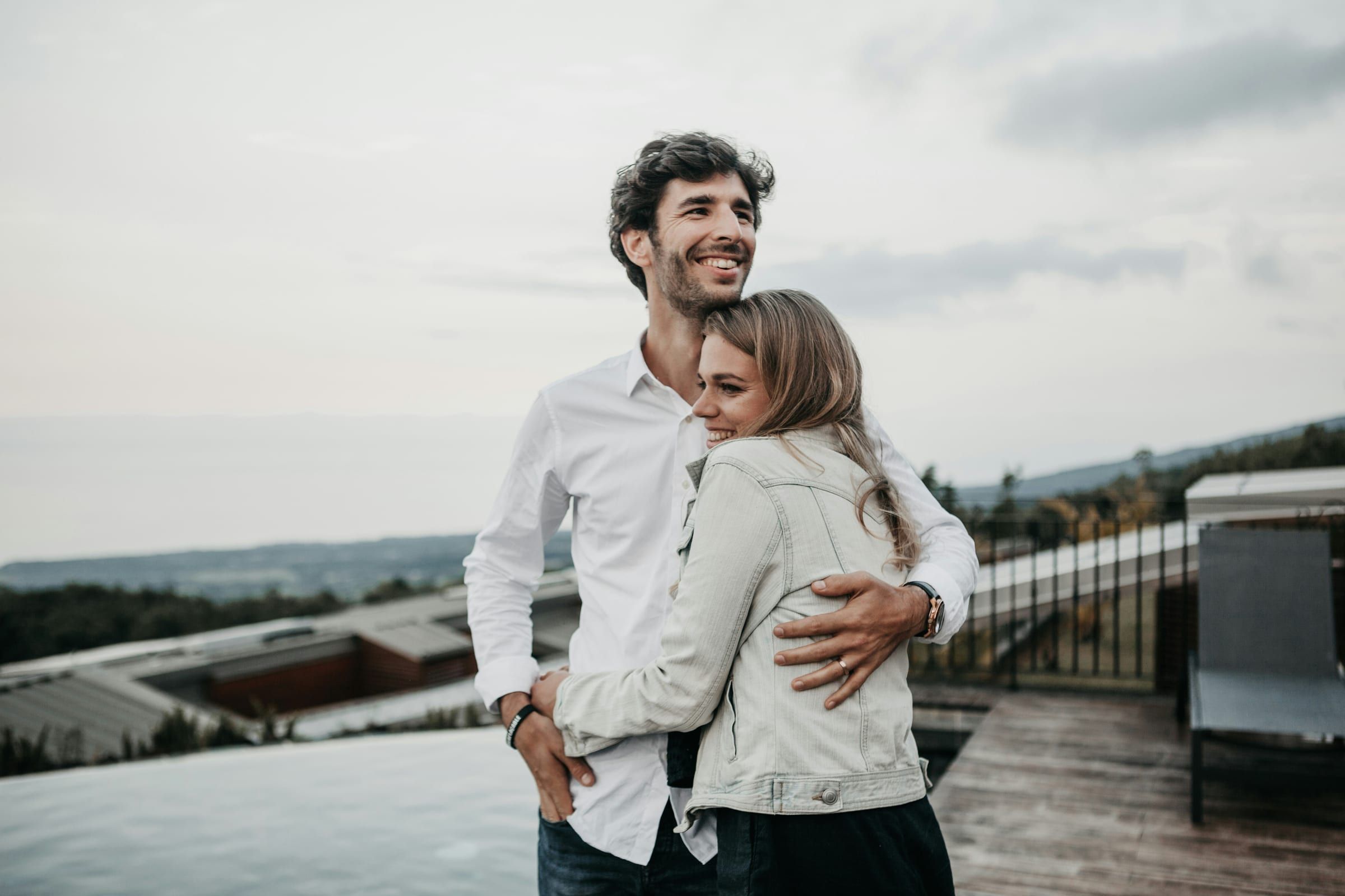 A couple standing together outdoors, looking into the distance.